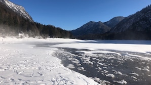 A frozen lake with snow-covered mountains and a clear sky.