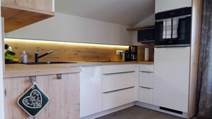 A modern kitchen with white cabinets, a wooden countertop, a built-in oven, and a coffee maker.