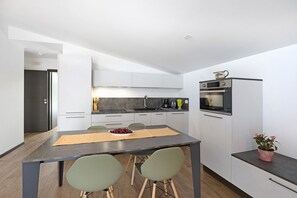 A modern kitchen with white cabinets, a dining table with chairs, and a small island with a plant.
