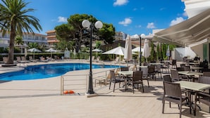 A poolside area with lounge chairs, umbrellas, and dining tables.
