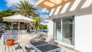 A rooftop pool area with lounge chairs, a table, and umbrellas.