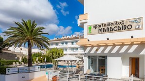 A hotel named 'Apartamentos Maracaito' with a pool area, outdoor seating, and a view of the surrounding buildings.