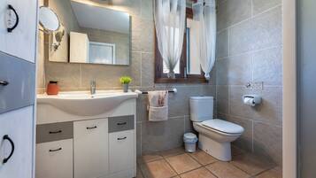 Un baño con lavabo, espejo, inodoro y cortina de ducha.