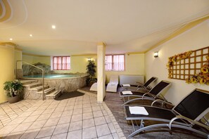 Un área de spa con un jacuzzi, sillones de descanso y una escalera que lleva a una piscina.