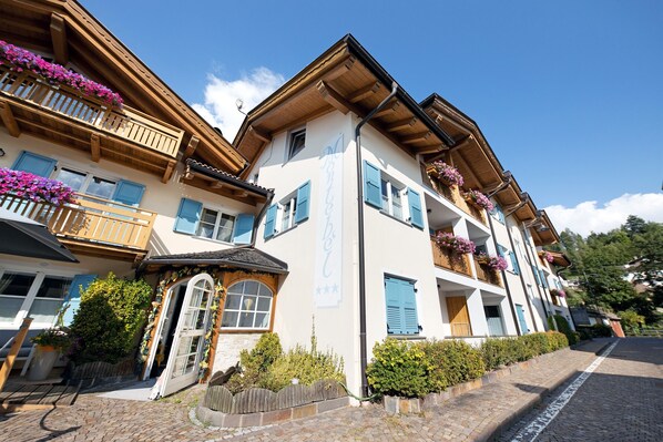 Un edificio de varios pisos con balcones, fachada de madera y macetas con flores.