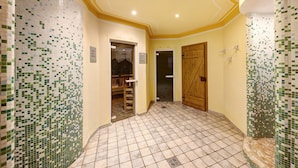 A hallway with tiled walls, a tiled floor, and a wooden door.