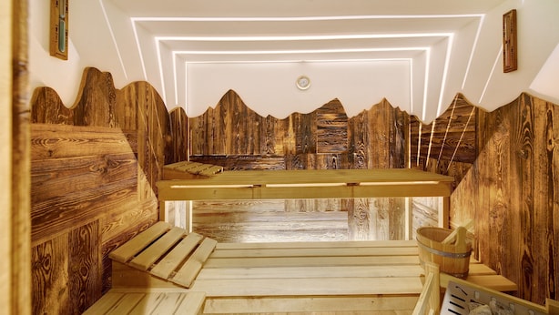 A wooden sauna with benches and a wooden wall design.
