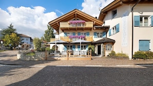 A hotel with a wooden facade, a balcony with flowers, and a cobblestone courtyard.