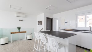 A modern kitchen with white bar stools, a glass partition, and a built-in island. - Holiday Apartment "Nerja Luxury" with Sea View, Terrace & Wi-Fi (Nerja)