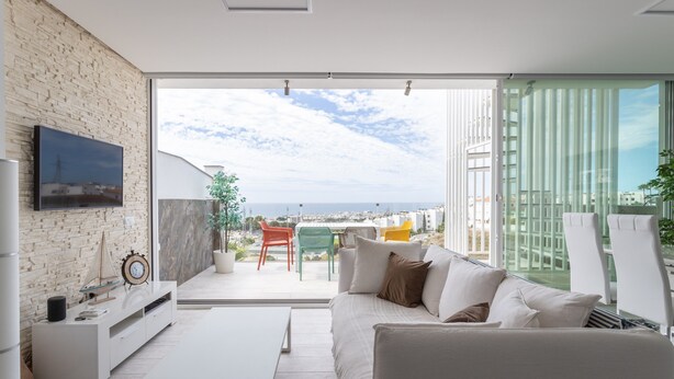 A modern living room with a sofa, TV, and a balcony with a view. - Holiday Apartment "Nerja Luxury" with Sea View, Terrace & Wi-Fi (Nerja)