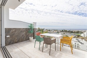 A balcony with a table and chairs, a potted plant, and a city view. - Holiday Apartment "Nerja Luxury" with Sea View, Terrace & Wi-Fi (Nerja)