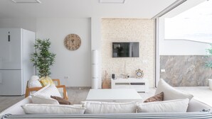 A modern living room with a sofa, a TV, a brick wall, and a large window. - Holiday Apartment "Nerja Luxury" with Sea View, Terrace & Wi-Fi (Nerja)