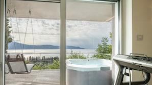 A balcony with a hot tub, a swing chair, and a view of a lake and mountains. - Exclusive Villa Agave with Lake & Mountain View, Pool, Whirlpool, and Sauna (Toscolano-Maderno)