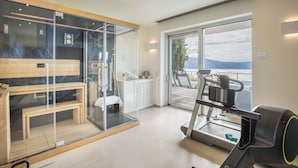 A modern room with a treadmill, a glass partition, a bench, and a view of the outdoors. - Exclusive Villa Agave with Lake & Mountain View, Pool, Whirlpool, and Sauna (Toscolano-Maderno)