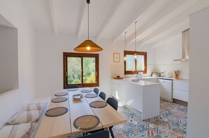 A modern kitchen with a central island, pendant lighting, and a dining area with a long table.
