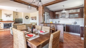 A dining area with a wooden table set for four, surrounded by wicker chairs. - Villa "Natalia" with Sea & Mountain View, Private Pool, Air Conditioning & Terrace (Nerja)
