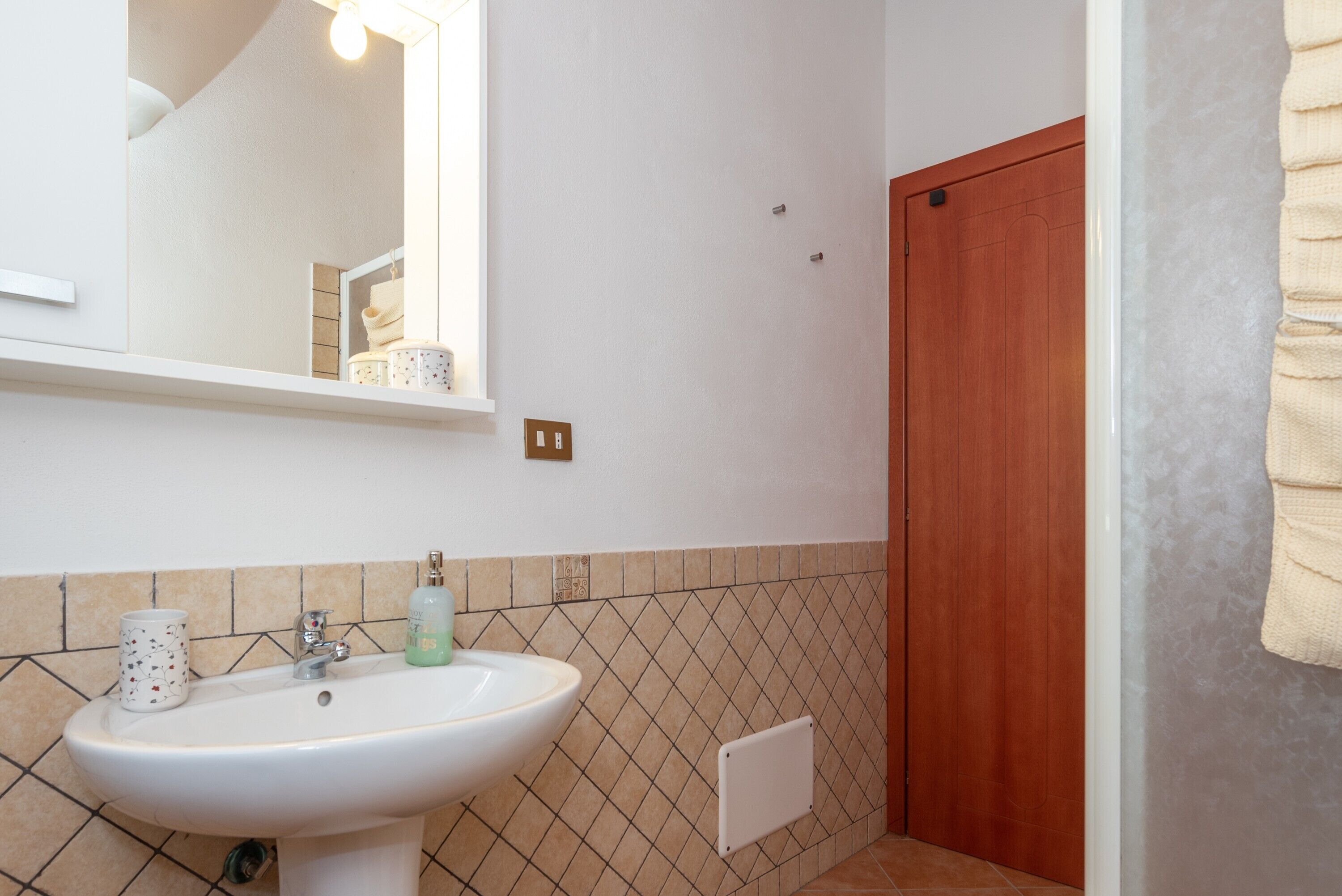 A bathroom with a white sink, a mirror, a towel rack, and a wooden door.