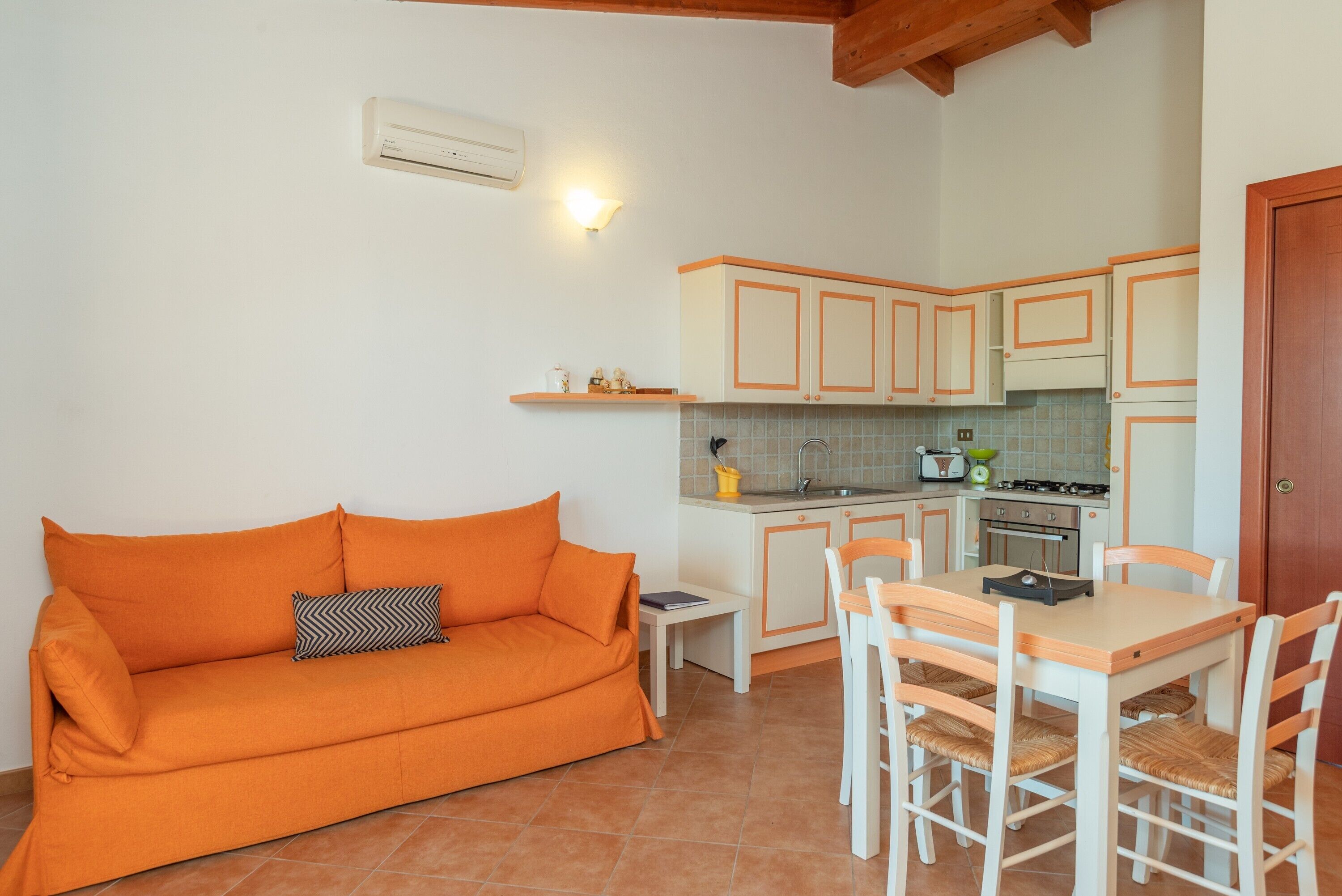 Cocina compacta con armarios blancos y una zona de comedor con mesa y sillas.