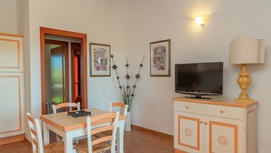 Ein Essbereich mit Tisch und Stühlen, einem Fernseher auf einem Schrank und gerahmten Kunstwerken an der Wand.