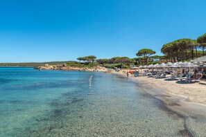 A beach with clear water, umbrellas, and trees. - Pet-Friendly Villa Diomede with Wi-Fi, Garden & Terrace (Santa Teresa Gallura)