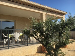 A building with a covered patio area, outdoor seating, and a small tree. - Les Mûriers Ardèche private fenced pool air-conditioned quiet space countryside (SAMPZON)