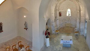 Una capilla con paredes de piedra, un altar central y estatuas religiosas.