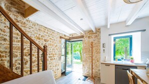 A cozy interior with a stone wall, wooden staircase, a white sofa, a dining area, and a kitchen with a window. - Holiday Home in Soturac with Private Pool (Soturac)