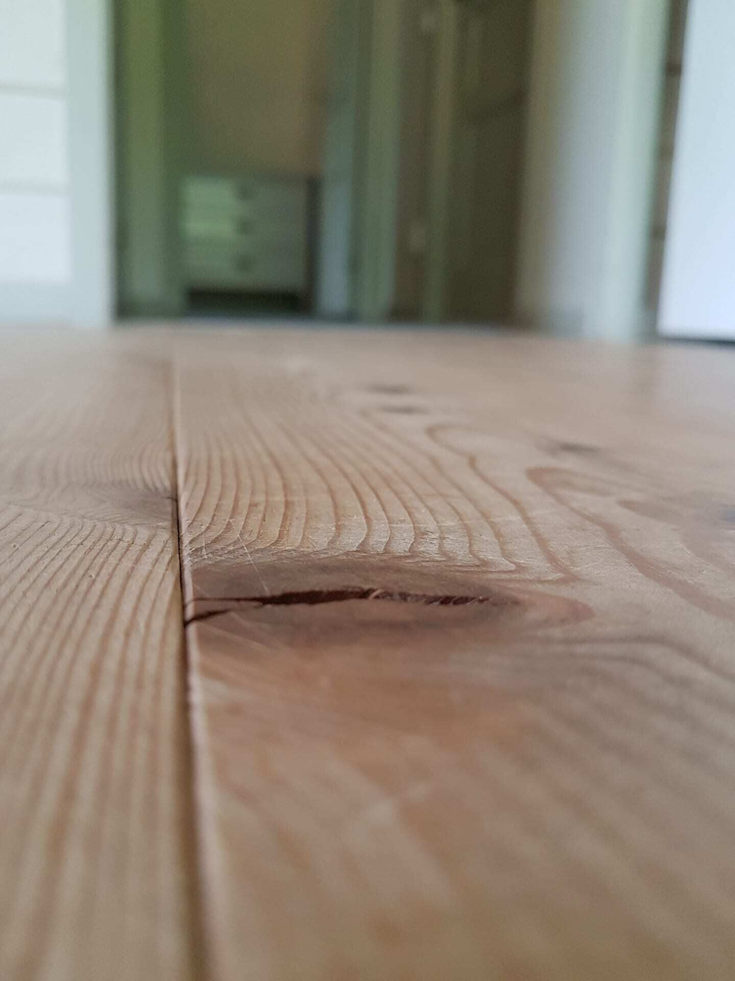 Primer plano de una superficie de madera con vetas marcadas y una pequeña grieta.