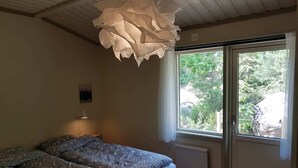 Un dormitorio con cama, ventana y lámpara en el techo.