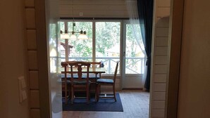 Una habitación con piso de madera, una mesa de comedor con sillas y vistas amplias a través de grandes ventanas.