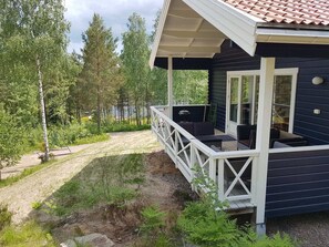 A dark blue cabin with a covered porch, outdoor seating, and a grill. - Stuga Ragnhild by the Lake Nerbjärken With Rowboat (Vena)