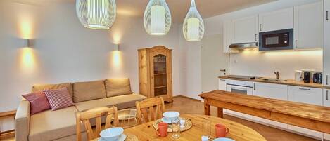 A modern kitchen with white cabinets, a microwave, and a wooden dining table set for four.