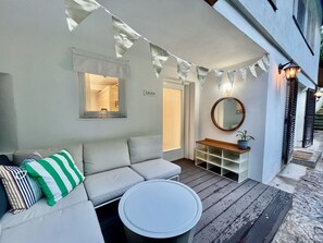 A cozy outdoor seating area with a sofa, cushions, a round table, and a wooden shelf with a potted plant. - Altstadt Apartments Melk - Deluxe Apartment Top 2 - Altstadt Apartments Melk (Melk)