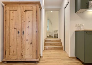 A hallway with a wooden wardrobe, a green cabinet, and a staircase leading to a dining area.