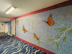 A hallway with a patterned wall, a red exit sign, and a patterned carpet. - "STEPS AWAY FROM THE WAIKIKI BEACH WITH OCEAN VIEW" (Honolulu)