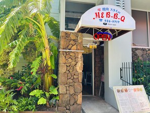 A restaurant entrance with a stone pillar, a sign indicating it's open, and a menu board outside. - "STEPS AWAY FROM THE WAIKIKI BEACH WITH OCEAN VIEW" (Honolulu)