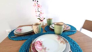 A dining table set with plates, bowls, and cups on blue placemats.