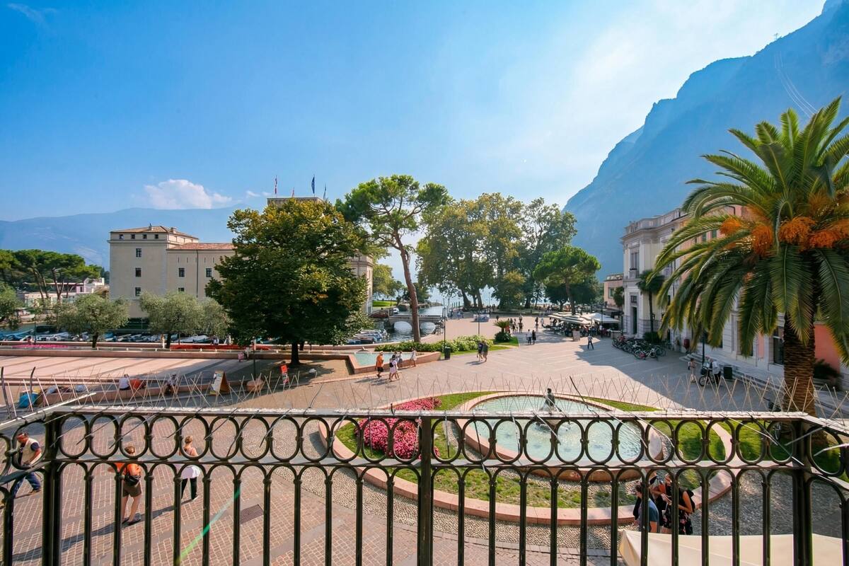 Une place publique avec une fontaine, des palmiers et des bâtiments en arrière-plan.