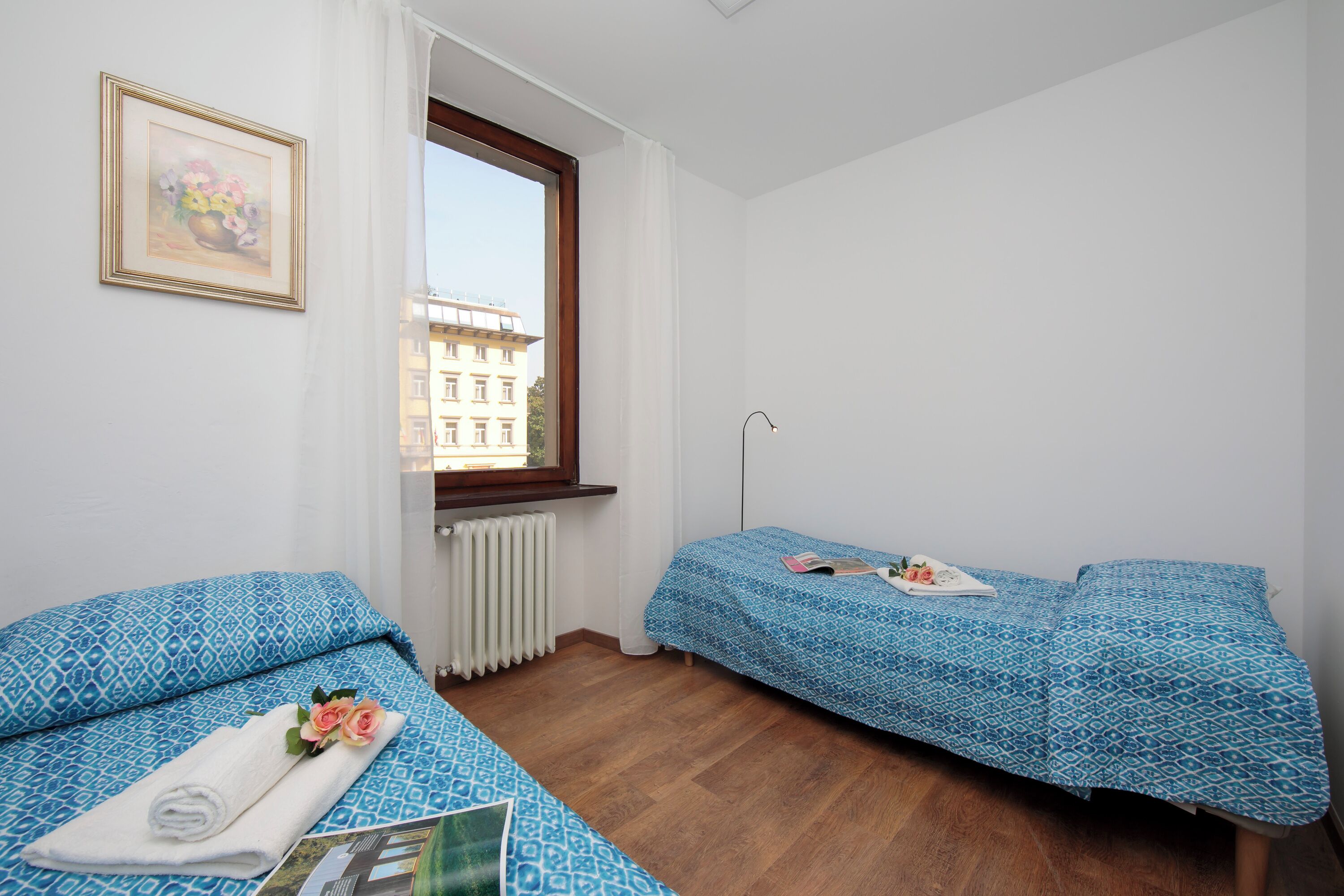 Ein kleines, sauberes Zimmer mit zwei Betten, einem Fenster und einer Heizung.