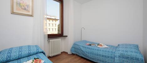 Ein kleines, sauberes Zimmer mit zwei Betten, einem Fenster und einer Heizung.