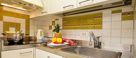 A modern kitchen with stainless steel appliances, a sink, and a countertop with a bowl of food and a pineapple.