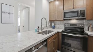 A kitchen with a stainless steel sink, a microwave, and an oven.