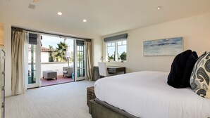 A spacious bedroom with a large bed, a desk, and a view of the outdoors. - "Casa Playa" in the heart of West Beach - impeccably remodeled, with A/C and 2 car garage! (Santa Barbara)
