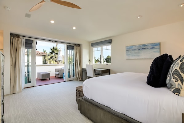 Um quarto espaçoso com uma cama grande, uma escrivaninha e vista para o exterior.