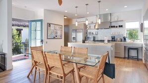 A modern kitchen with a glass dining table, wicker chairs, and a ceiling fan. - "Casa Playa" in the heart of West Beach - impeccably remodeled, with A/C and 2 car garage! (Santa Barbara)
