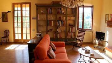 Ein gemütliches Wohnzimmer mit einer großen Bücherwand, einer bequemen Couch und einem Fernseher.