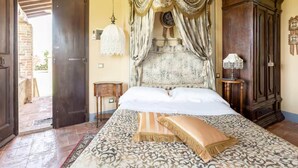 A bedroom with a large bed, a canopy, a small table, and a wardrobe.