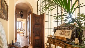 A room with a wooden desk, a chair, a large plant, and a bookshelf filled with books. - Stone house villa with Spa in Cortona (Cortona)