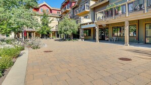 A courtyard with a brick pathway, surrounded by multi-story buildings with balconies and storefronts, including a visible sign for 'Dreams of Owls Books'. - Half-Mi to Payette Lake: Dtwn McCall Condo! (McCall)