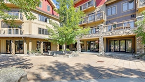 A multi-story hotel with balconies, a central courtyard with a tree, and stone pillars. - Half-Mi to Payette Lake: Dtwn McCall Condo! (McCall)